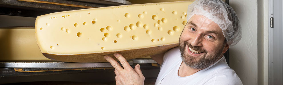 Käsermeister mit zwei Angestellten vor Käselaiben